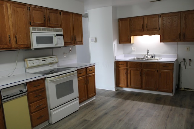 kitchen with white appliances, dark wood-style floors, brown cabinets, light countertops, and a sink