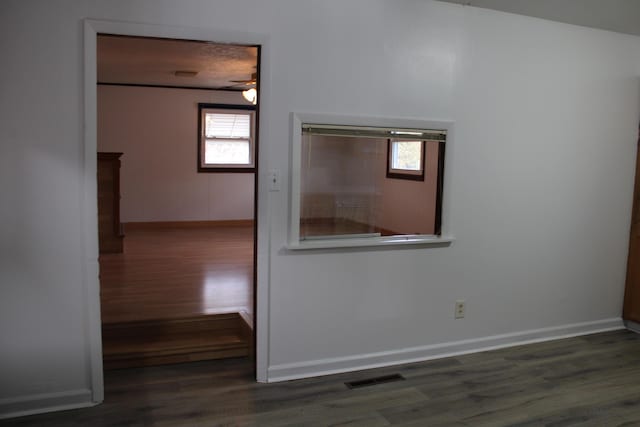 unfurnished room with a healthy amount of sunlight, visible vents, baseboards, and wood finished floors