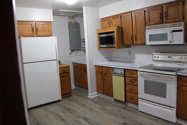 kitchen featuring brown cabinetry, light countertops, white appliances, and electric panel