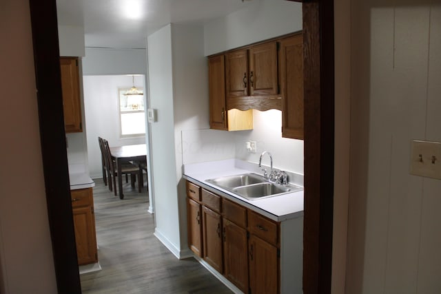 kitchen with dark wood-style floors, brown cabinetry, light countertops, and a sink