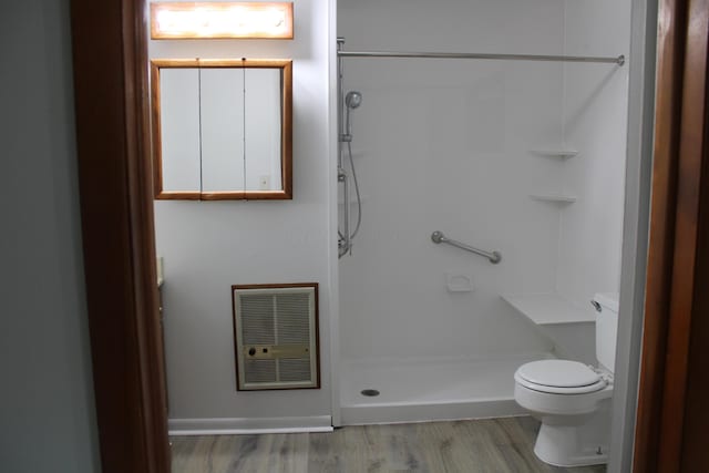 bathroom with heating unit, toilet, a shower, and wood finished floors