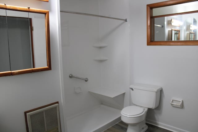 bathroom featuring baseboards, visible vents, a shower, toilet, and wood finished floors