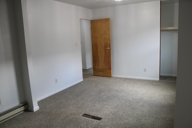 unfurnished bedroom with carpet, a closet, visible vents, baseboard heating, and baseboards