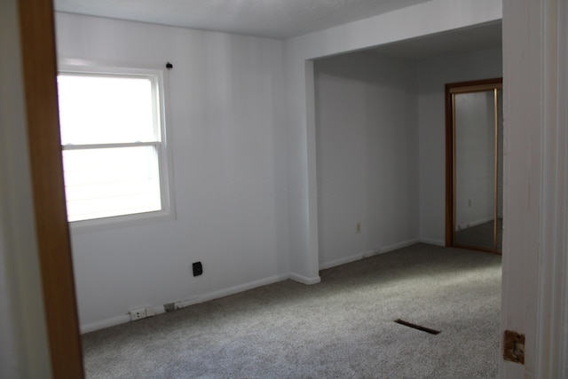 carpeted empty room featuring visible vents and baseboards