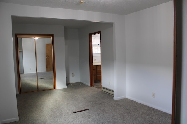 unfurnished bedroom featuring connected bathroom, a baseboard heating unit, carpet floors, baseboards, and a closet