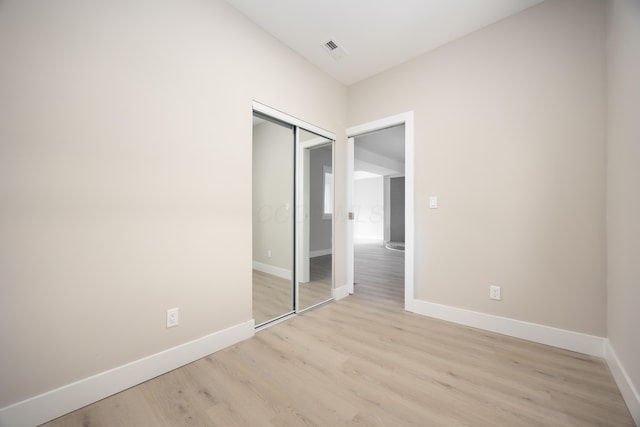 unfurnished bedroom featuring light hardwood / wood-style floors and a closet