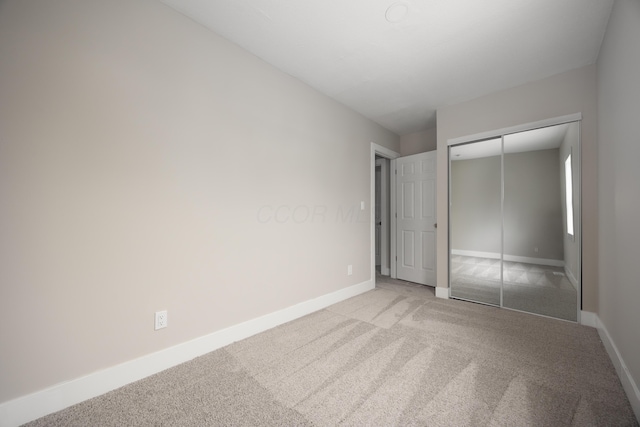 unfurnished bedroom with light colored carpet and a closet