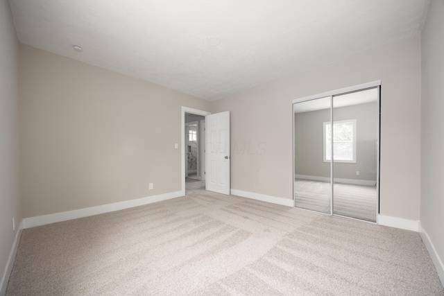 unfurnished bedroom featuring a closet and light carpet