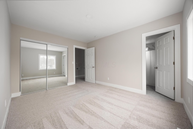 unfurnished bedroom featuring light carpet and a closet