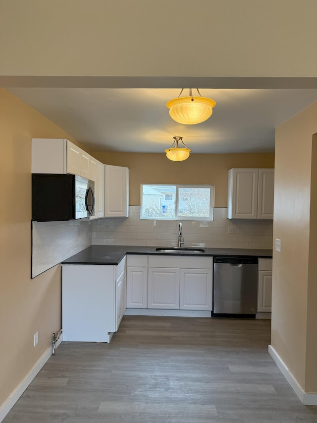 kitchen with sink, hanging light fixtures, dishwasher, decorative backsplash, and white cabinets