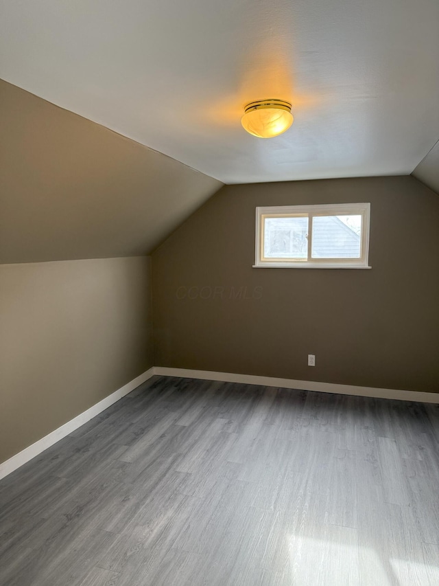 additional living space with vaulted ceiling and dark wood-type flooring