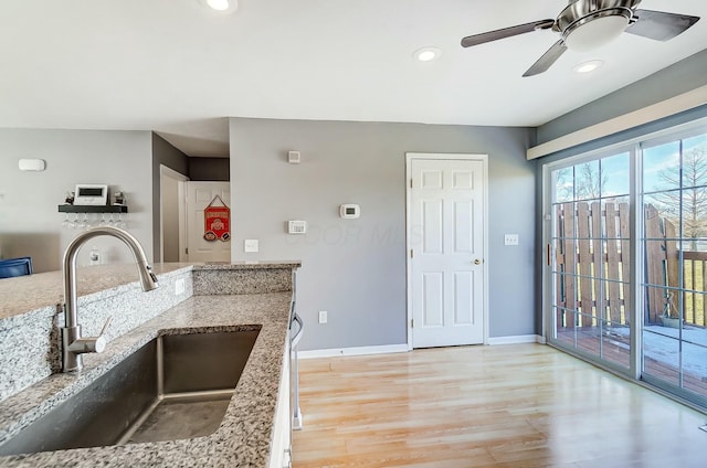 kitchen featuring light stone counters, sink, light hardwood / wood-style floors, and ceiling fan