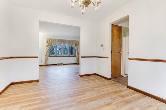 spare room with a chandelier and light hardwood / wood-style floors