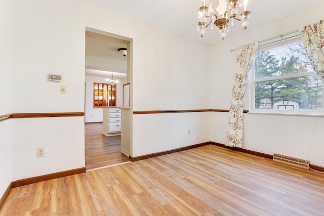 unfurnished room featuring hardwood / wood-style floors and a chandelier