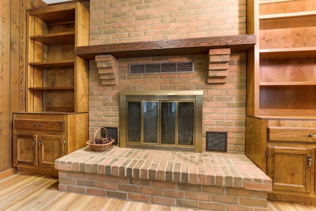 interior details featuring built in features, hardwood / wood-style floors, and a brick fireplace