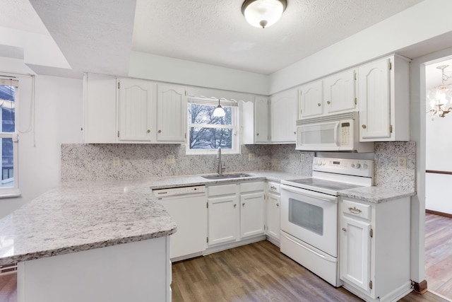 kitchen with sink, white appliances, dark wood-type flooring, white cabinetry, and kitchen peninsula