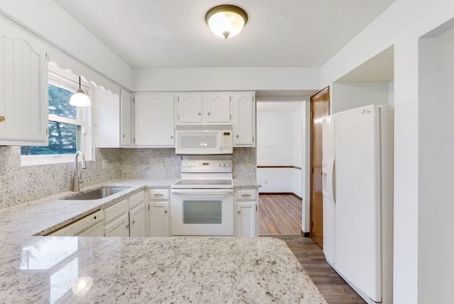 kitchen featuring hardwood / wood-style floors, sink, backsplash, white cabinets, and white appliances