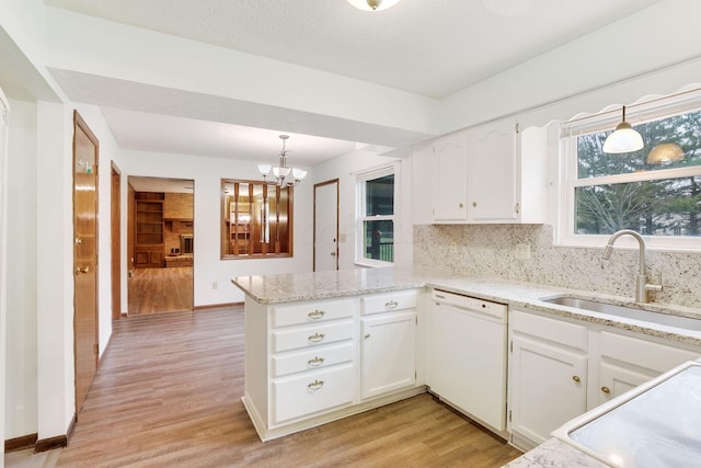 kitchen featuring sink, dishwasher, white cabinetry, hanging light fixtures, and kitchen peninsula