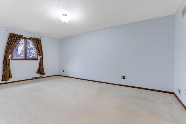 carpeted empty room featuring a textured ceiling