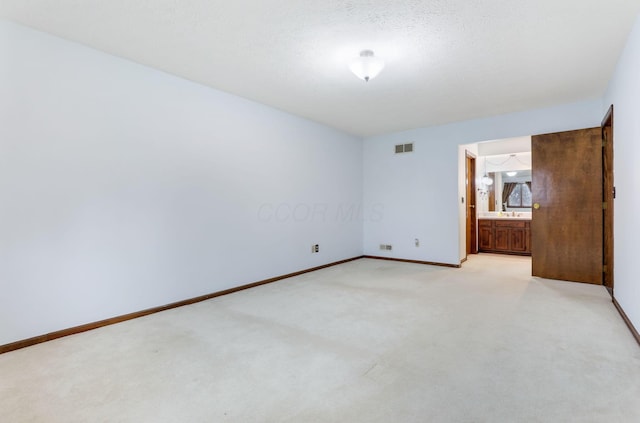 unfurnished bedroom with connected bathroom, light colored carpet, and a textured ceiling