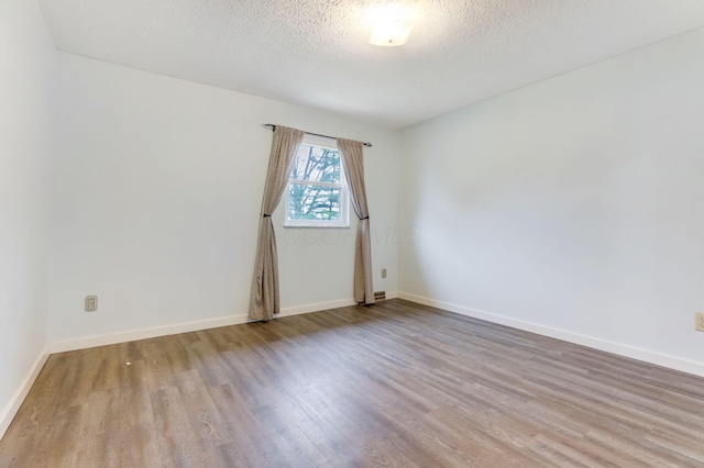 unfurnished room with a textured ceiling and light wood-type flooring