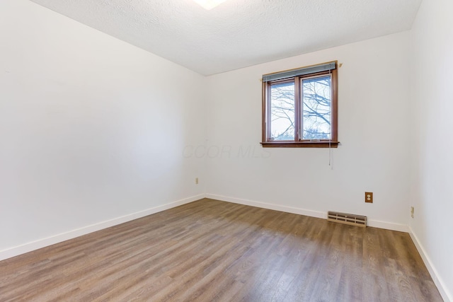 empty room featuring wood-type flooring and a textured ceiling