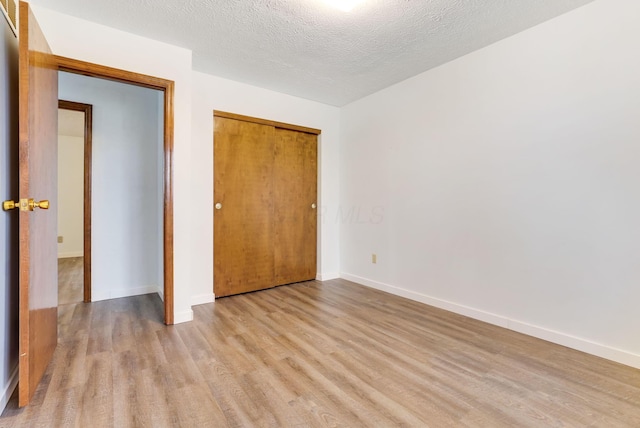 unfurnished bedroom featuring light hardwood / wood-style floors, a closet, and a textured ceiling