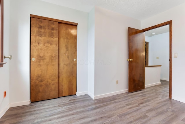 unfurnished bedroom with a closet, a textured ceiling, and light hardwood / wood-style flooring