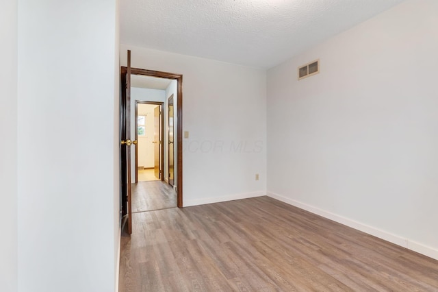 unfurnished room with light hardwood / wood-style floors and a textured ceiling