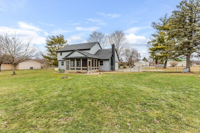 rear view of house featuring a sunroom and a lawn