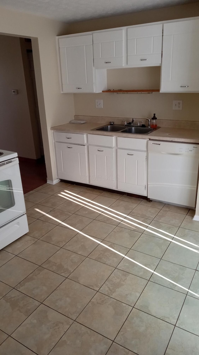 kitchen with white cabinetry, sink, light tile patterned floors, and white appliances