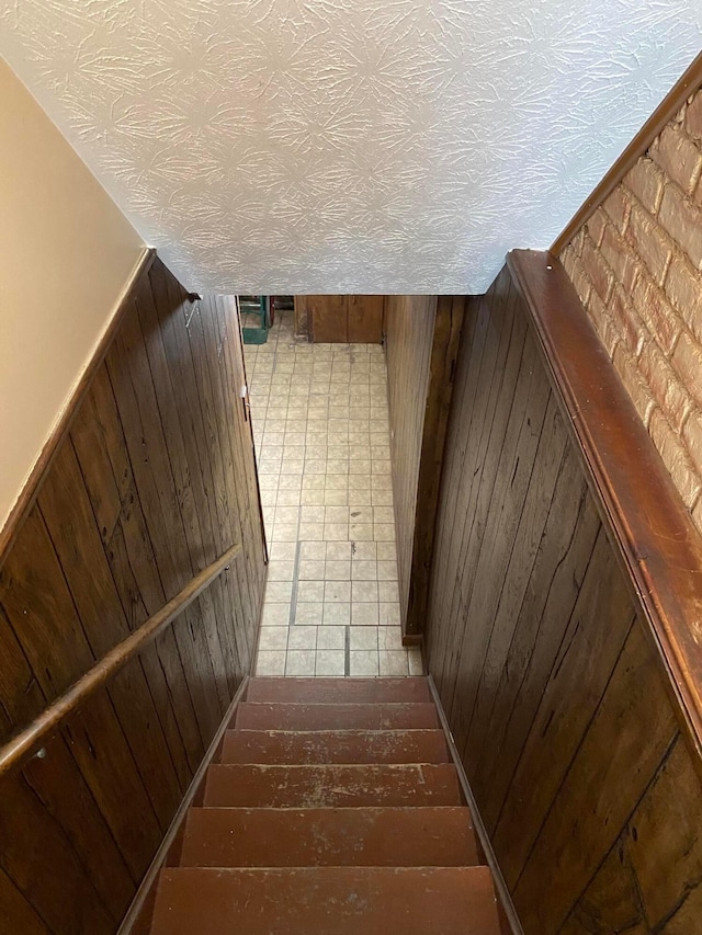 stairs featuring wooden walls and a textured ceiling