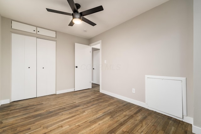 unfurnished bedroom featuring ceiling fan, dark hardwood / wood-style flooring, and a closet