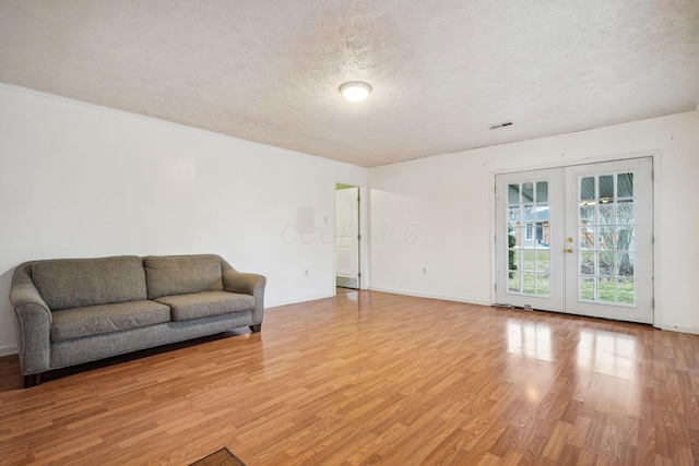 unfurnished living room with french doors, light hardwood / wood-style flooring, and a textured ceiling