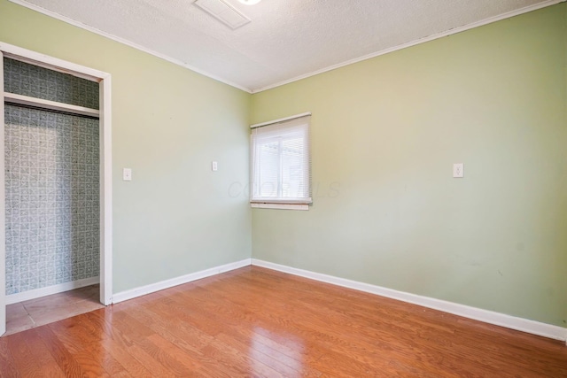 unfurnished bedroom featuring hardwood / wood-style flooring, ornamental molding, and a textured ceiling