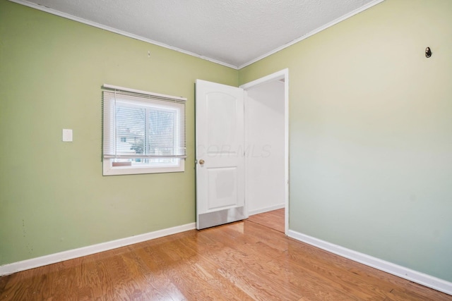 empty room featuring crown molding, light hardwood / wood-style floors, and a textured ceiling