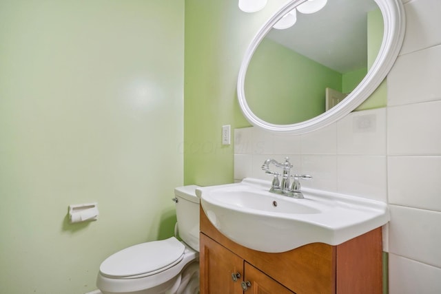 bathroom featuring tasteful backsplash, vanity, tile walls, and toilet