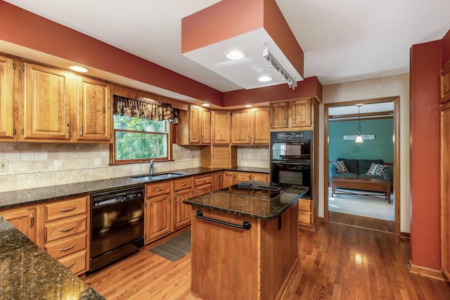 kitchen with a kitchen island, wood-type flooring, sink, dark stone countertops, and black appliances