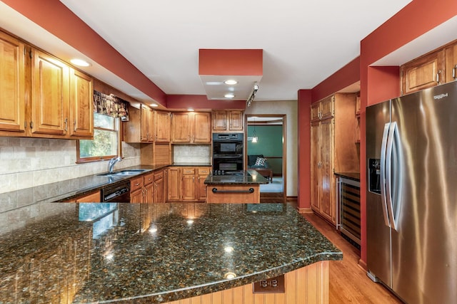 kitchen with wine cooler, sink, dark stone countertops, kitchen peninsula, and black appliances