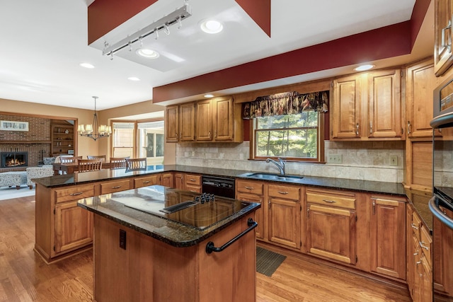 kitchen featuring sink, a center island, black appliances, decorative light fixtures, and kitchen peninsula