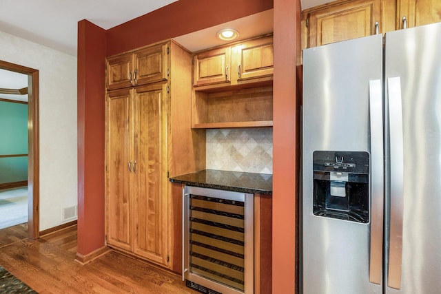 kitchen featuring dark hardwood / wood-style floors, wine cooler, stainless steel fridge, and dark stone counters