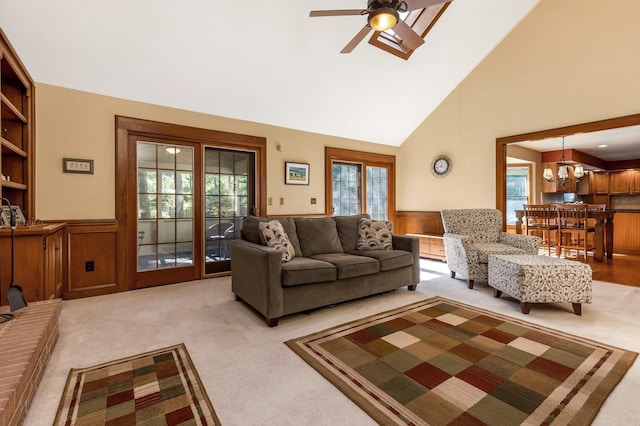 carpeted living room with plenty of natural light, ceiling fan with notable chandelier, high vaulted ceiling, and built in shelves