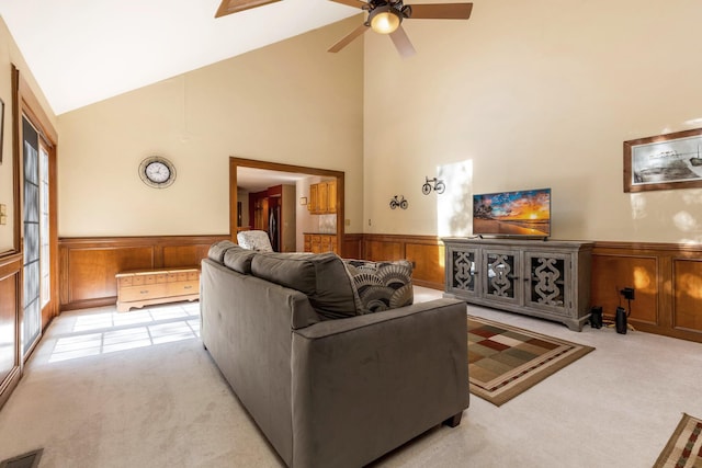 living room with ceiling fan, high vaulted ceiling, and light carpet