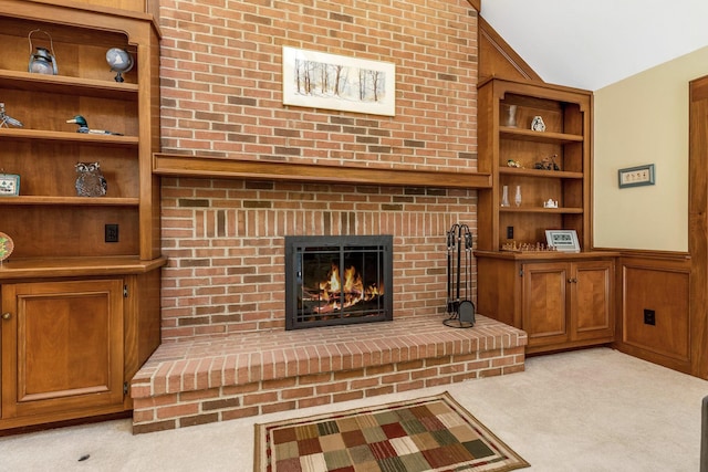 carpeted living room with built in shelves, lofted ceiling, and a brick fireplace