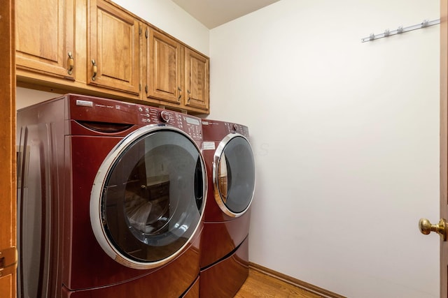 laundry area featuring cabinets, washer and dryer, and light wood-type flooring