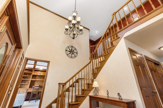 staircase featuring a notable chandelier, ornamental molding, and a high ceiling