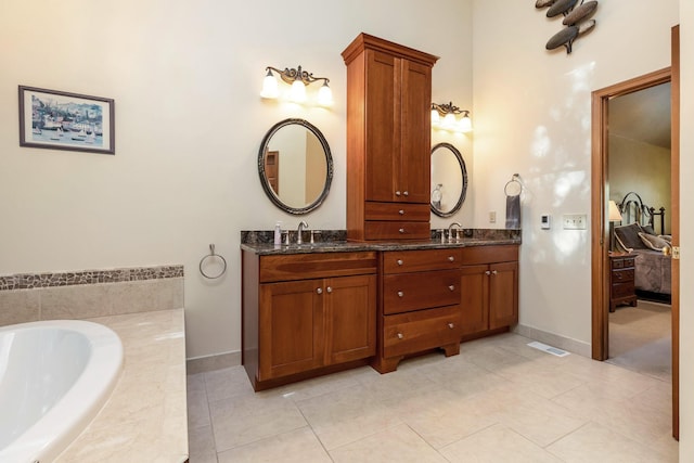 bathroom with tiled tub, vanity, and tile patterned flooring