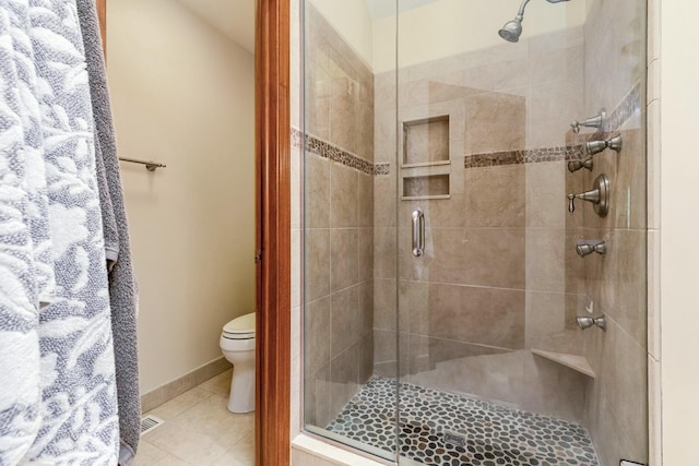 bathroom with tile patterned flooring, a shower with door, and toilet