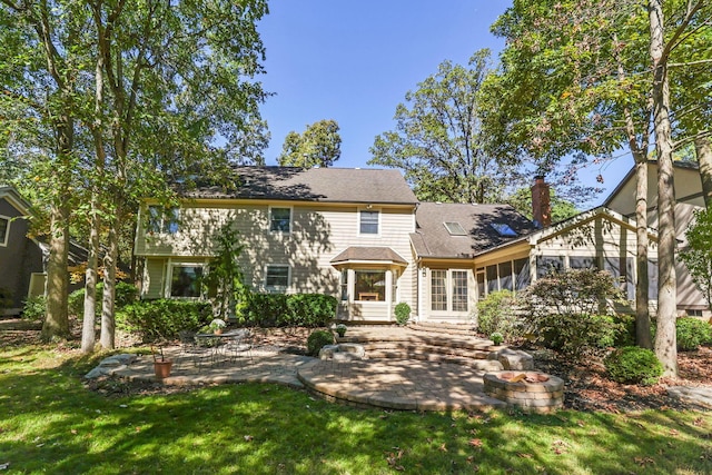 back of property with a yard, a sunroom, and a patio