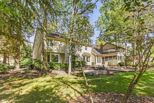 rear view of house featuring a patio, a sunroom, and a lawn